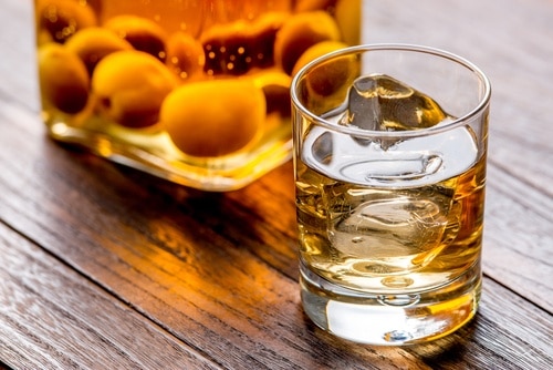 Umeshu in a glass with ice and bottle next to it